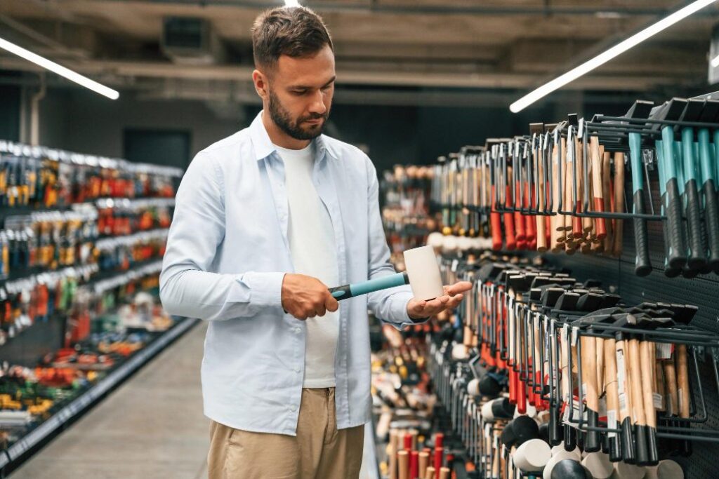 Hammer in hands man is in the hardware shop