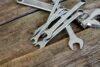 Different types of wrenches including adjustable, combination arranged on a wooden table.
