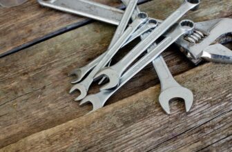 Different types of wrenches including adjustable, combination arranged on a wooden table.