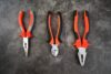 Different types of pliers including needle-nose, slip-joint, and locking pliers arranged on a workbench