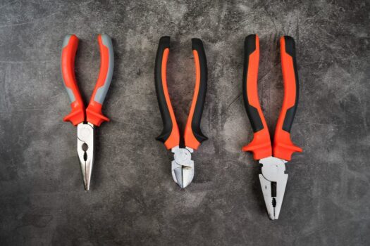 Different types of pliers including needle-nose, slip-joint, and locking pliers arranged on a workbench